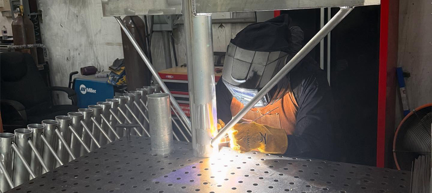 A Divine Lighting Employee Welding a Fixture Arm